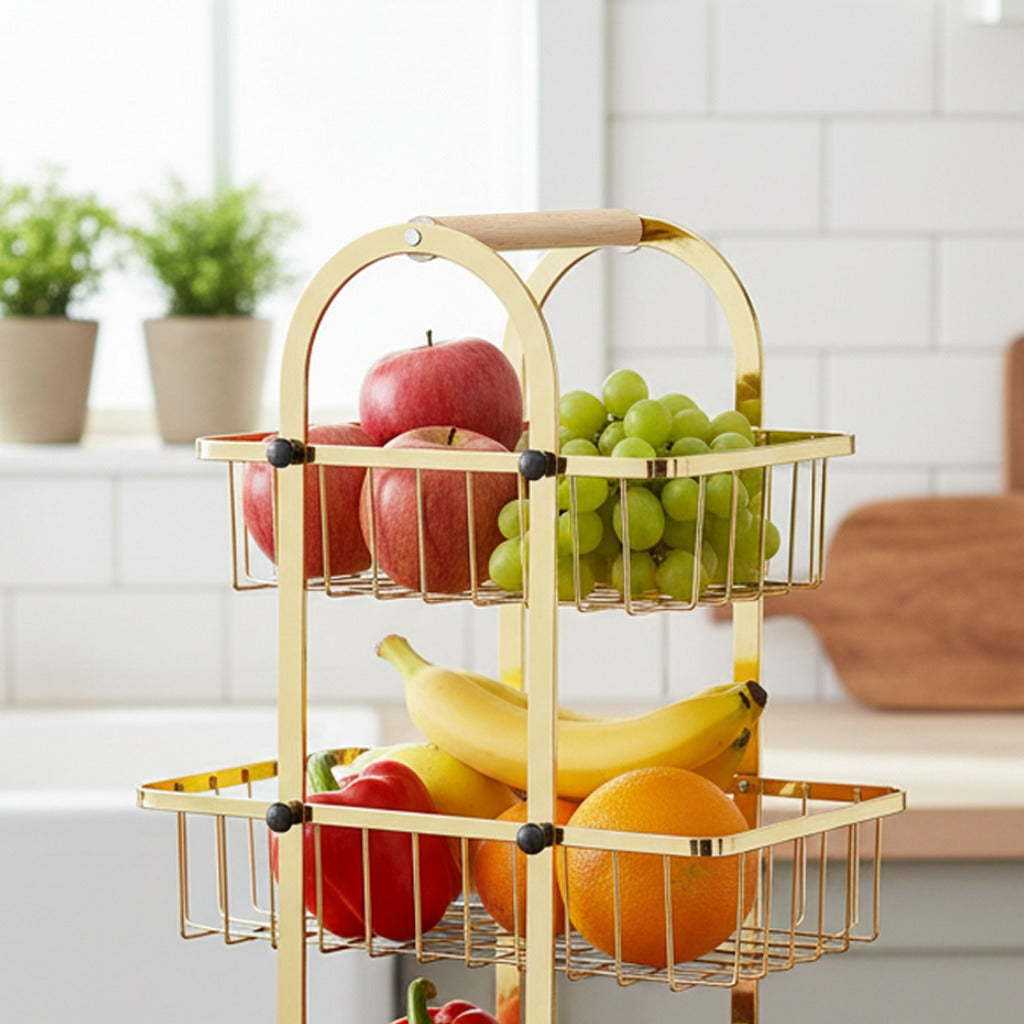 Gold three-tiered fruit basket with apples, grapes, and bananas on a kitchen counter.