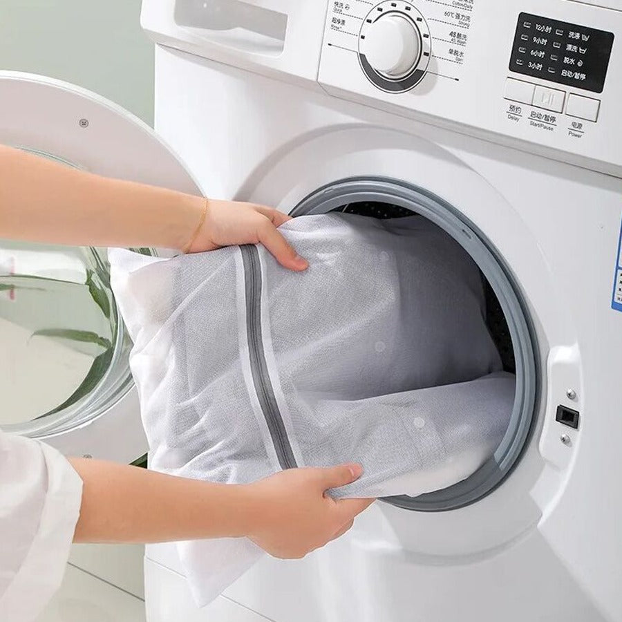 A Person is inserting cloth to a washing machine using 4 Pcs Mesh Laundry Washing Bags Set.