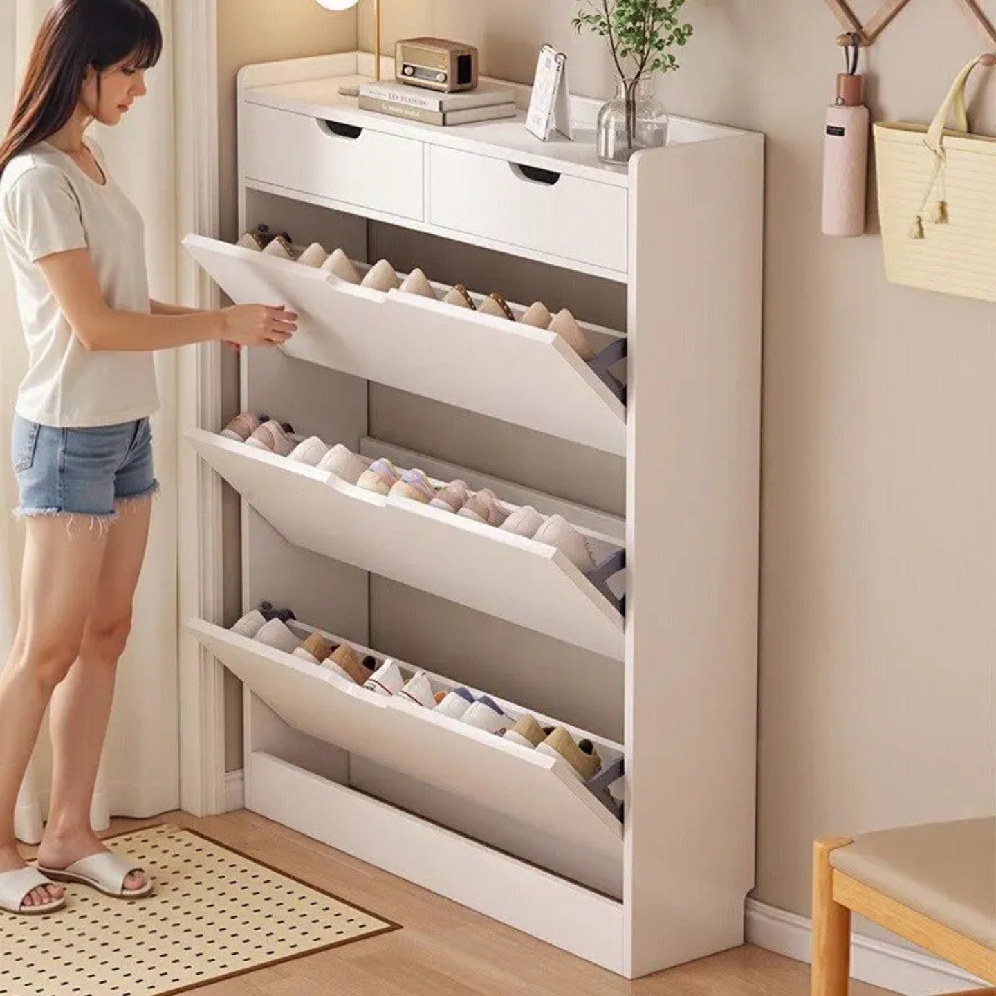 A Woman is Opening the slim shoe cabinet with flip drawers that neatly stores shoes while saving space, with a top surface for décor or essentials.