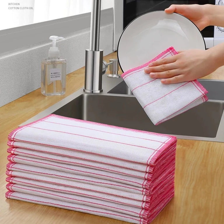 A person is cleaning a plate with the help of a Kitchen Dishwashing Cloth next to a stack of Absorbent Stain Removal Towels