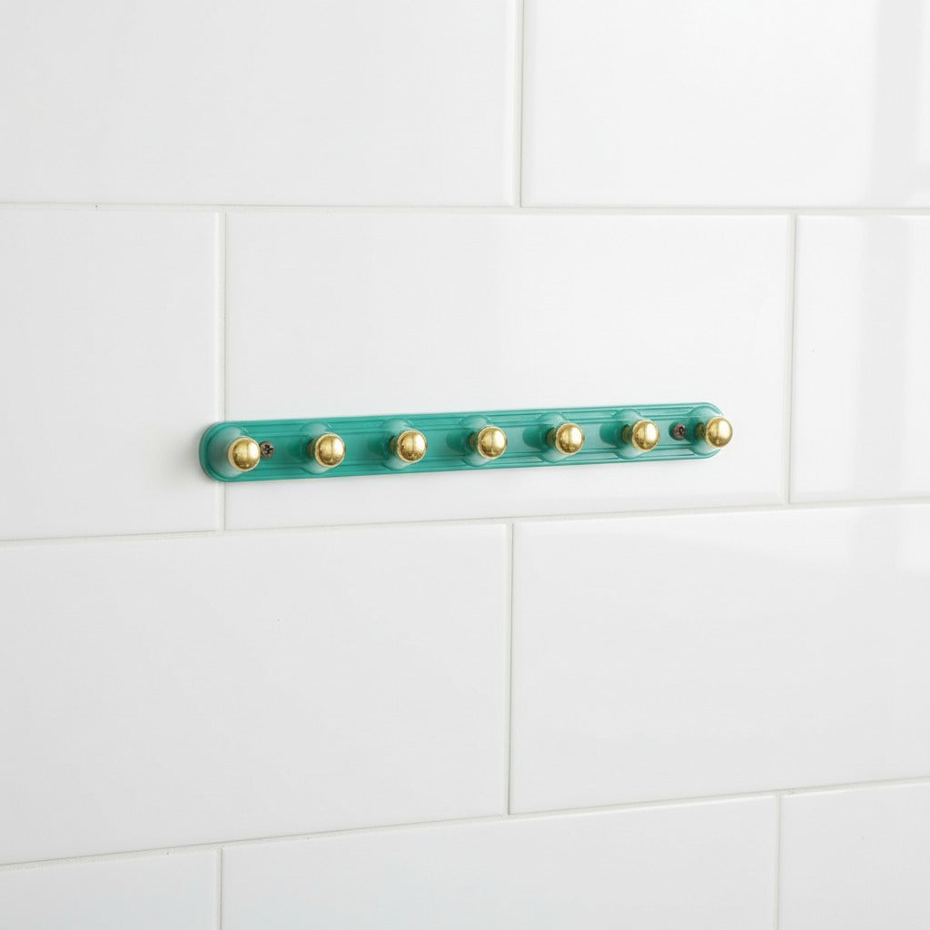 Green Adhesive Wall Hooks with gold hooks on a white tiled wall