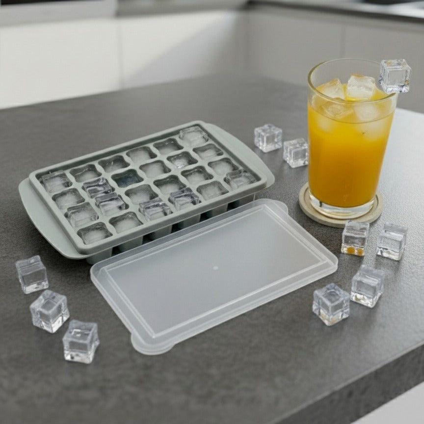 An Ice Cube Tray is Placed on a Kitchen Cabinet Along with a Glass Of Juice.