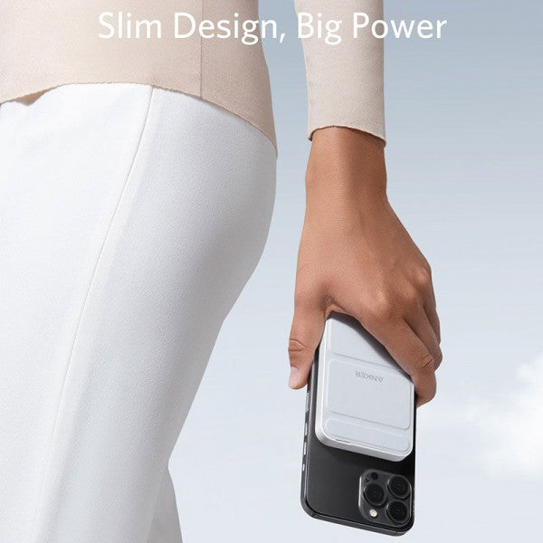 A person is holding a 5000 mAh wireless portable charger along with their mobile phone