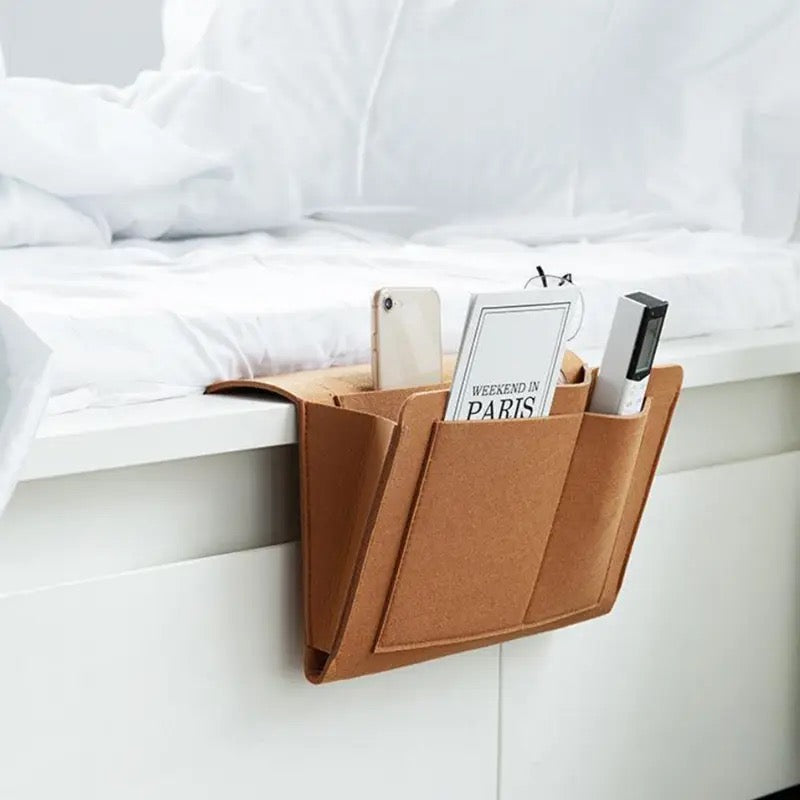 Felt Bedside Storage Bag placed next to the bed with some items