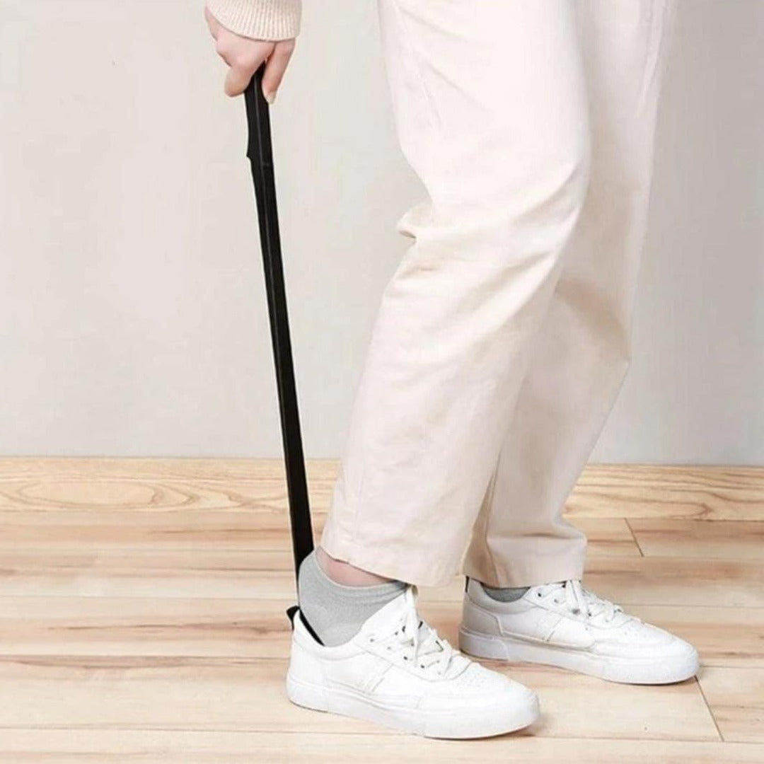 A Person is Wearing Shoe Using Long Handle Shoe Horn.