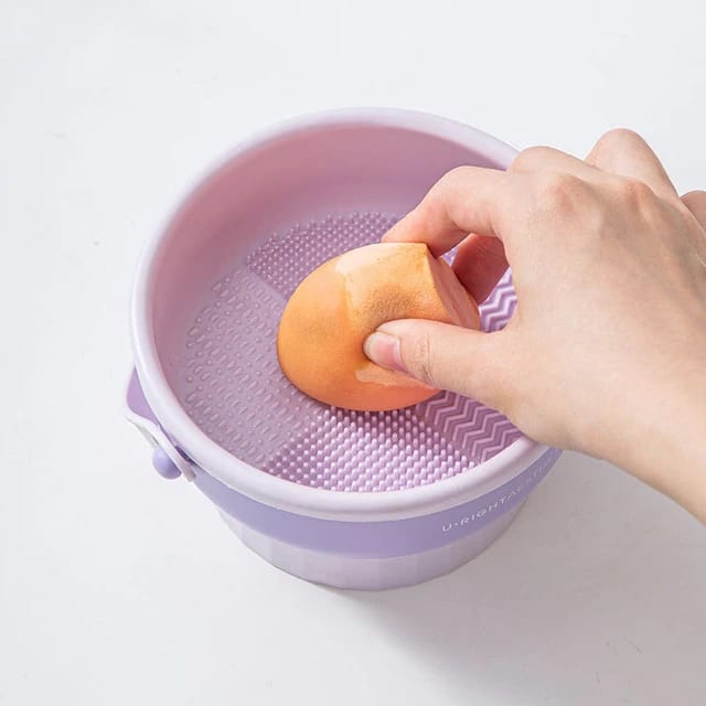 Someone holding a sponge on Makeup Brush Cleaning Mat with Brush Drying Holder