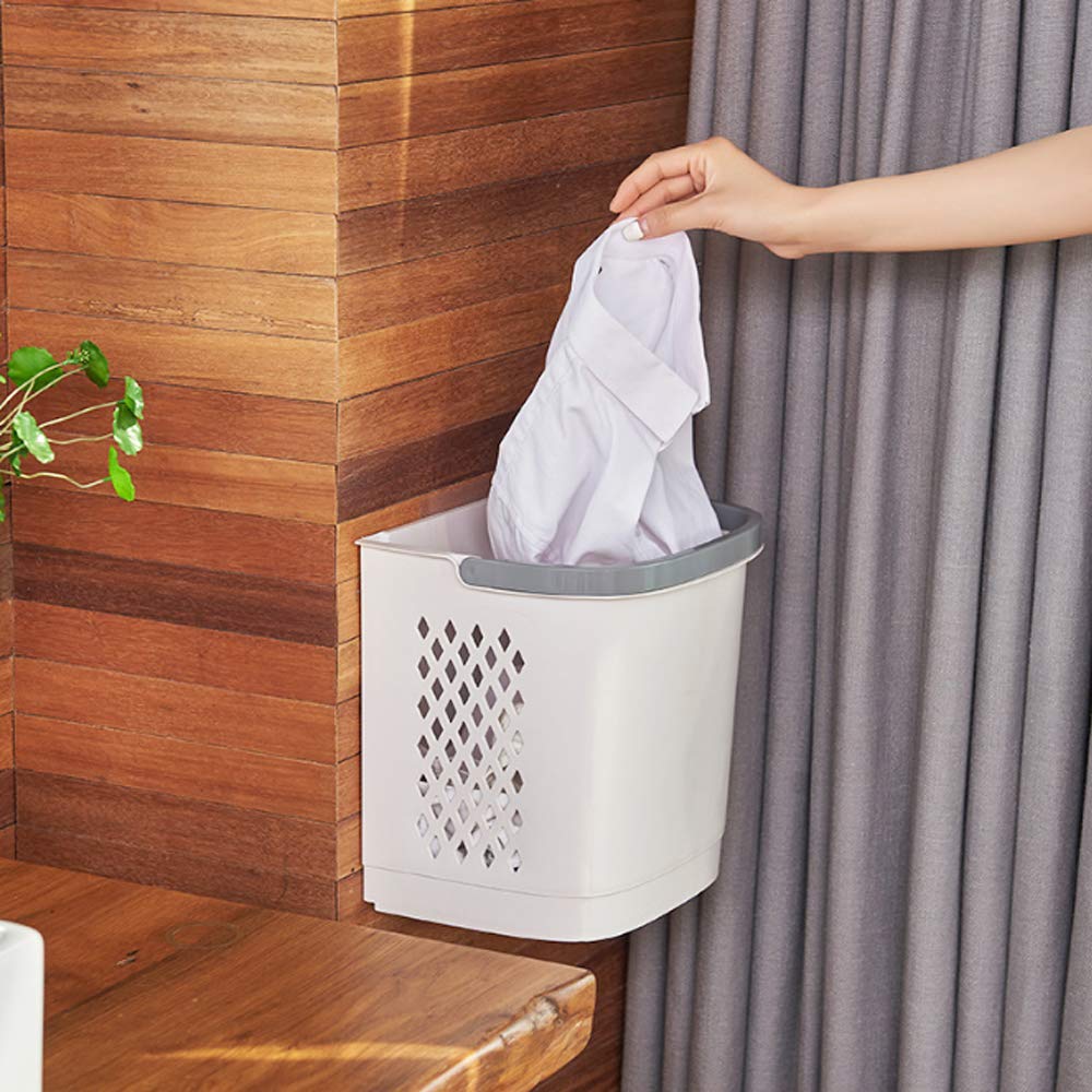 A person placing a shirt into a wall-mounted laundry basket.