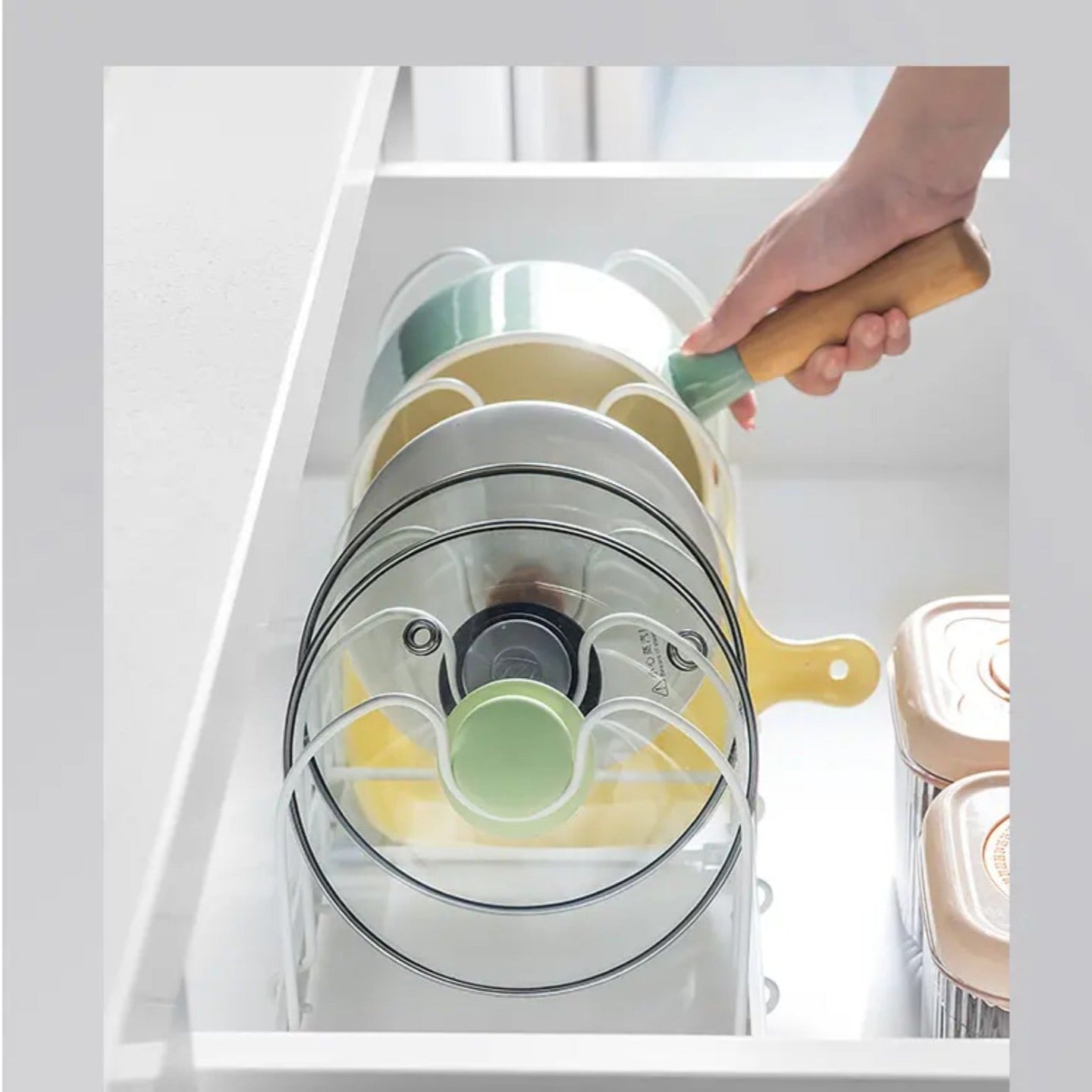 A Person is Taking Utensils From Expandable Pot and Pan Organizer Rack Organized with Pans and Plates.