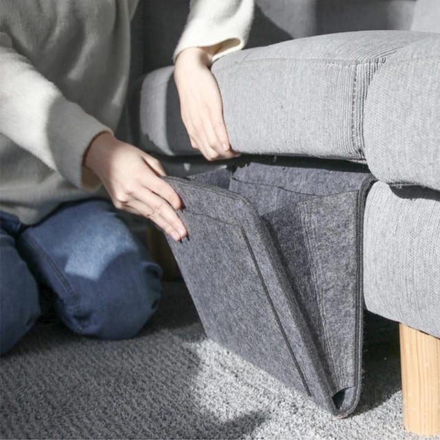 Someone installing Felt Bedside Storage Bag into the sofa