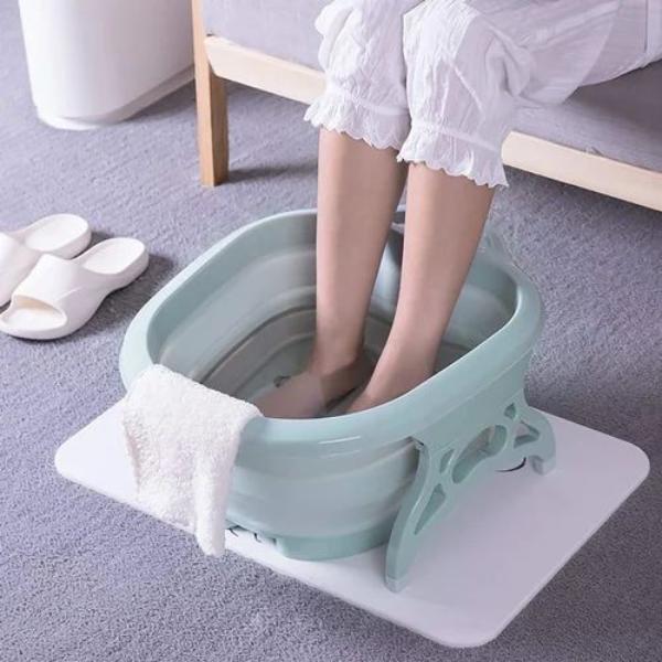 A Women is Dipped Her Leg in Folding Foot Tub Portable Foot Wash Tub Massage Bucket.