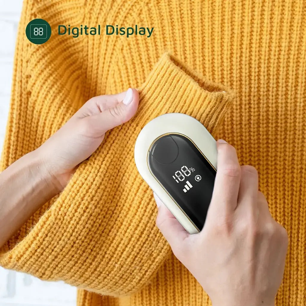 A person using the Green Lion DualPro Digital Fabric Remover on a yellow knitted sweater. The device’s digital display is clearly visible, showing its power and status indicators