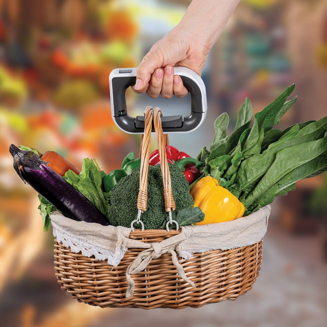 A person using the Green Lion Travel Mate Digital Luggage Scale to easily lift and weigh a basket filled with groceries, showing its ergonomic handle and accurate digital weight display