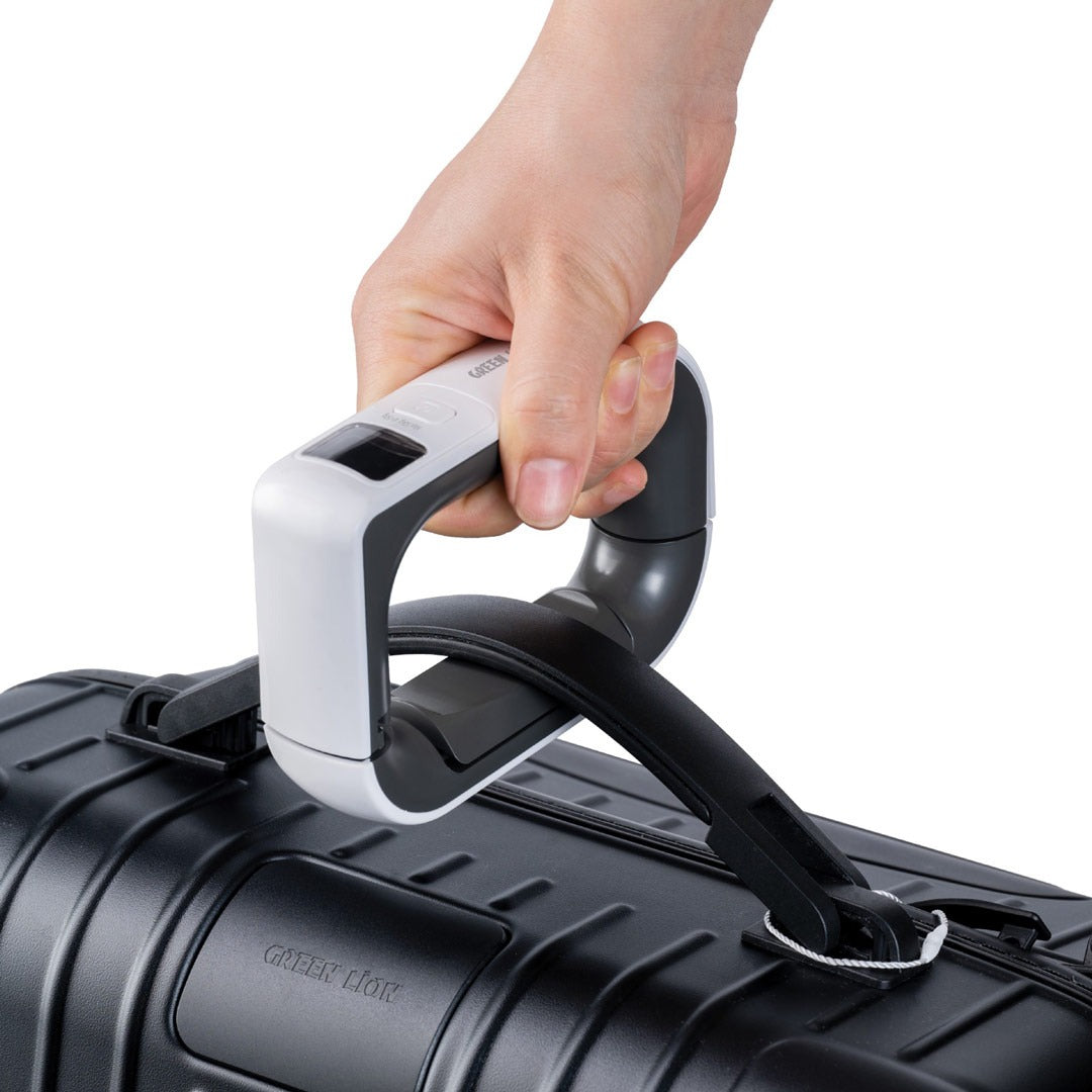 A person using the Green Lion Travel Mate Digital Luggage Scale to weigh a suitcase, demonstrating its ergonomic grip and precise digital display