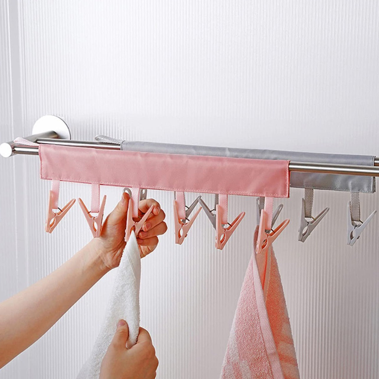 A person using a multi-clip hanger to hang towels