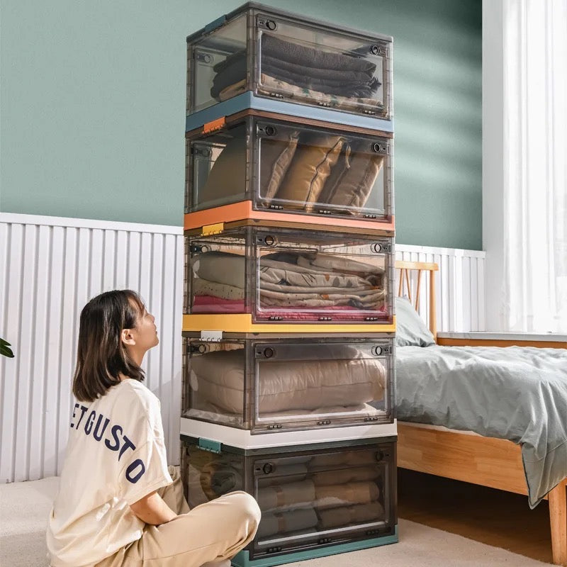 A woman sits beside a stackable plastic storage boxes