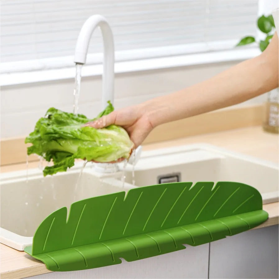 Kitchen Sink Splash Guard installed on a sink in which a person is washing lettuce