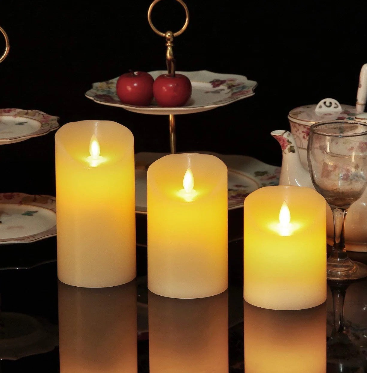 3 Flameless LED Candles in different sizes lit up and  placed on a dining table near to utensils