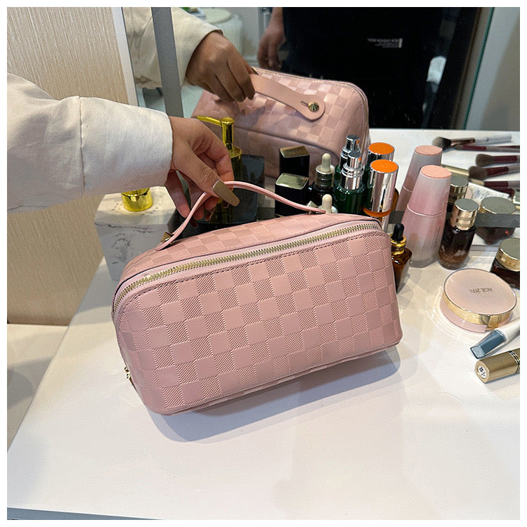 A person tending to place a Pink color Cosmetic Bag on a makeup table with few cosmetic products in it