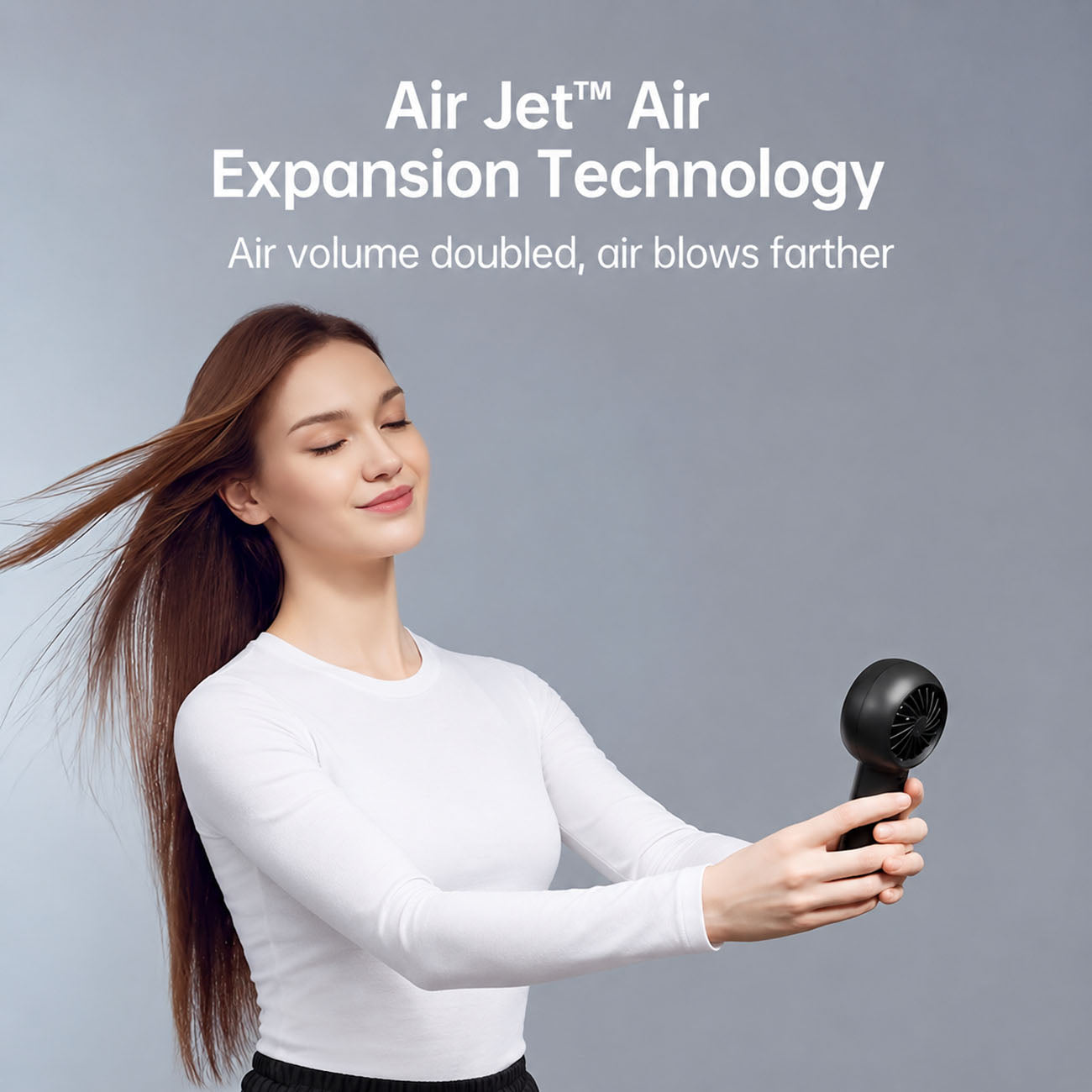 A woman with long brown hair wearing a white long-sleeve top holds a JisuLife Handheld Fan Life5 Plus against her hair, with text at the top reading 'Air Jet Air Expansion Technology' and 'Air volume doubled, air blows farther.'.