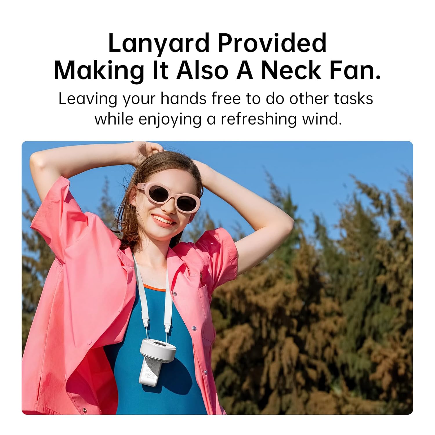 A person using a neck fan with a lanyard, keeping their hands free, smiling while enjoying the outdoors.