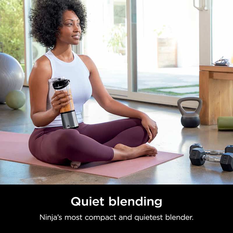 A Woman is Holding Ninja Blast Portable Blender While Doing Yoga.