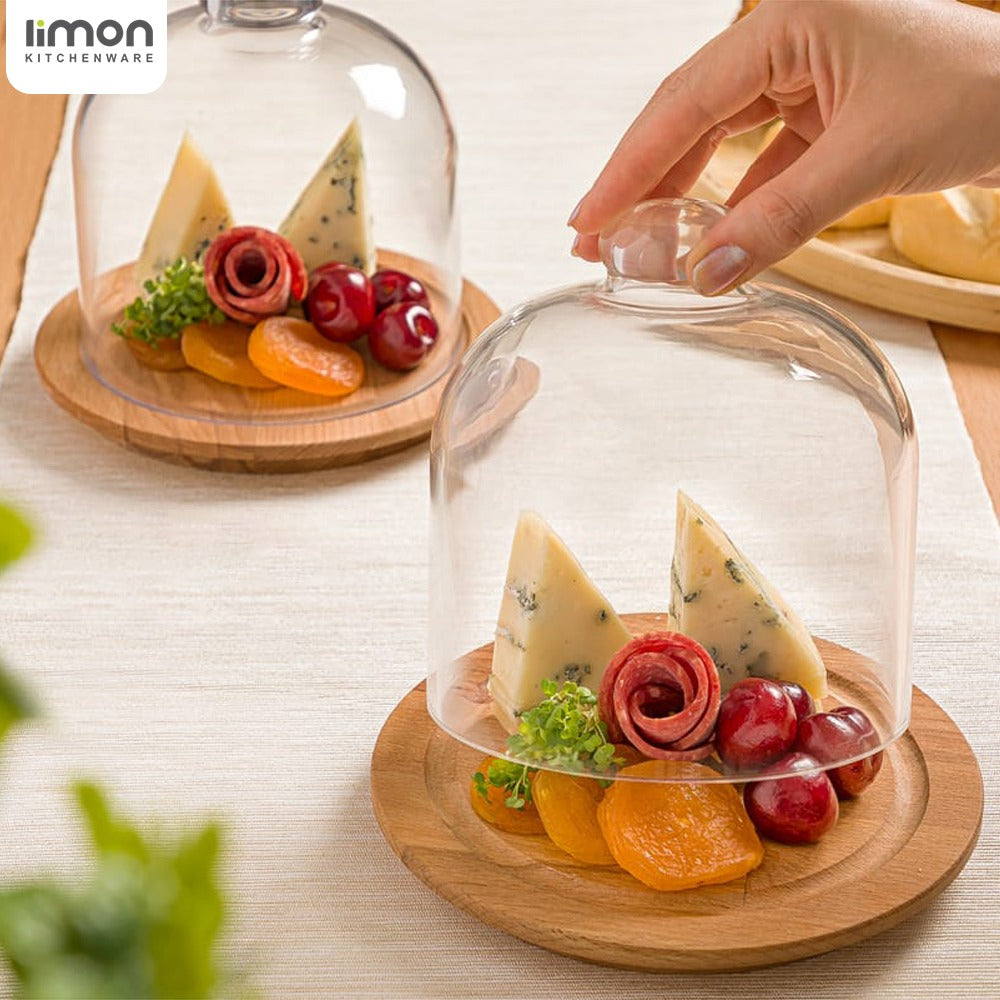A Person is Opening Desert Dome with Wooden Base Filled with Desserts.