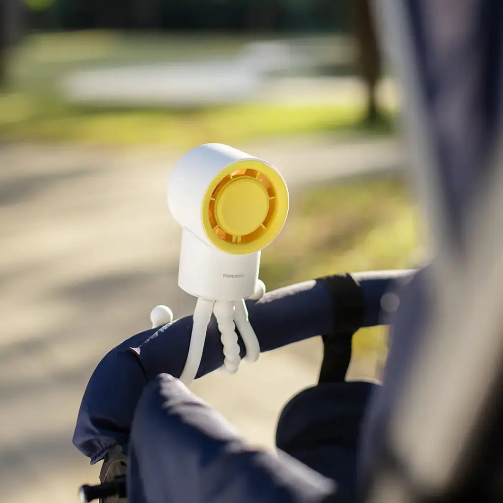 White and yellow Porodo CoolFlex Mini Handheld Fan on a blurred outdoor background