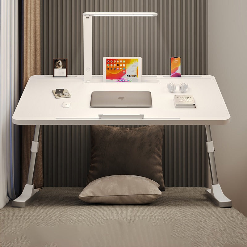 Portable foldable laptop bed desk table with adjustable legs and built-in LED lamp, arranged with laptop and other essentials.