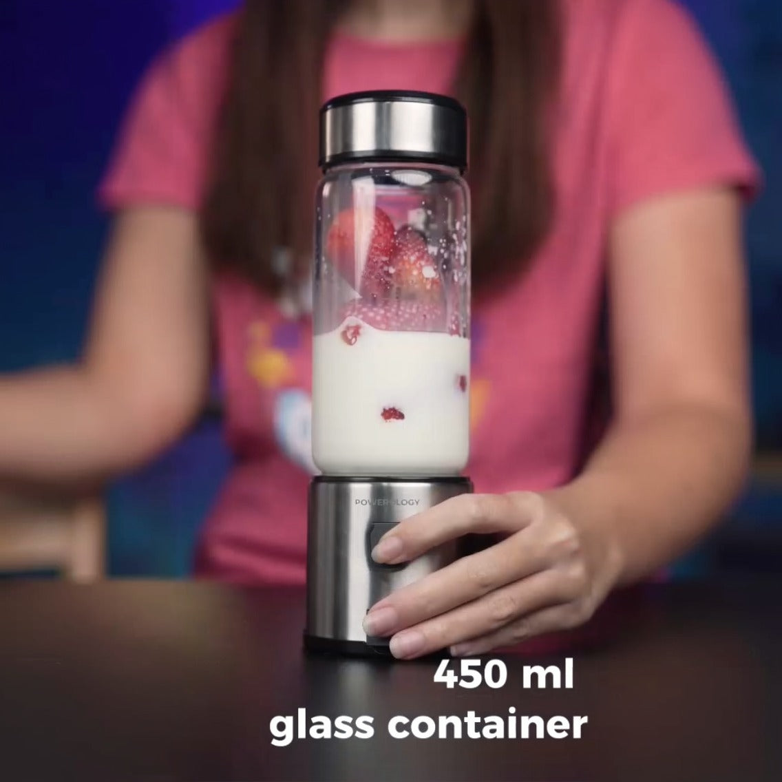 Person holding a Powerology 6-Blade Portable Juicer with a glass container filled with a smoothie.