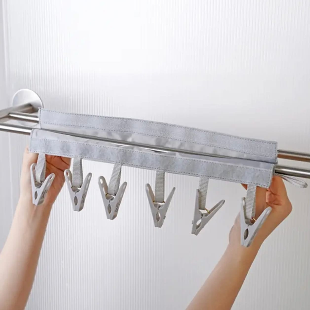 A person hanging a Gray color multi-clip hanger
