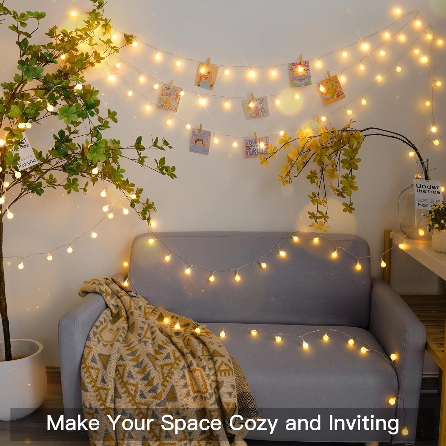Cozy living room with string lights, plants, and a gray sofa.