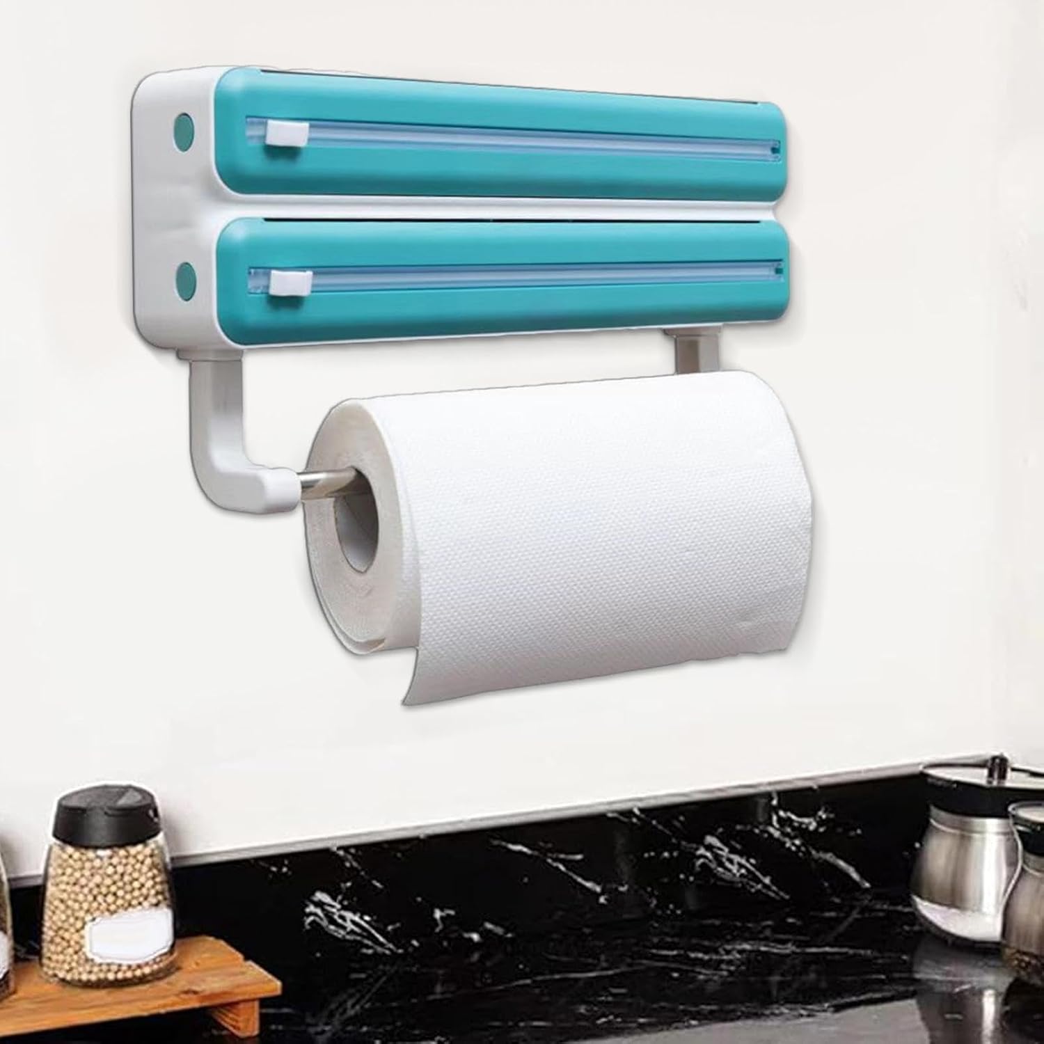 A wall-mounted triple paper dispenser is shown, designed for kitchen convenience and organization. It features two upper compartments for storing and cutting cling film, aluminum foil, or plastic wrap, each with built-in sliding cutters. Below, there is a holder for a paper towel roll, allowing easy access for cleaning.