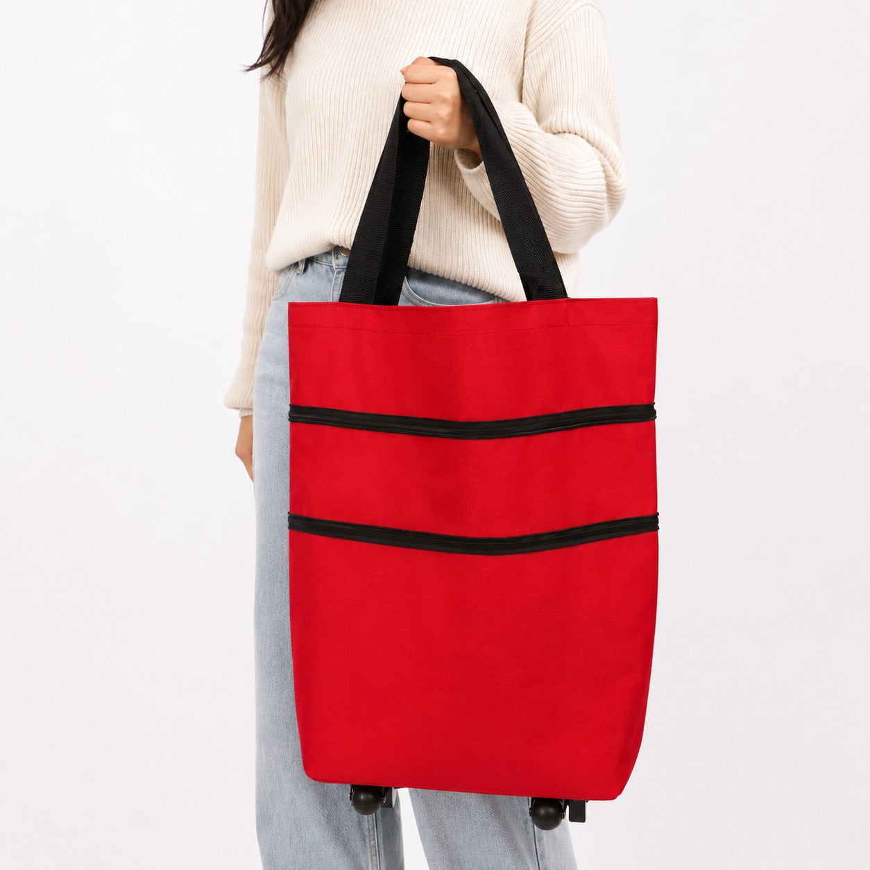 A person wearing a cream ribbed sweater and light blue jeans holds a Shopping Trolley Bag with black handles and black horizontal trim against a plain white background.