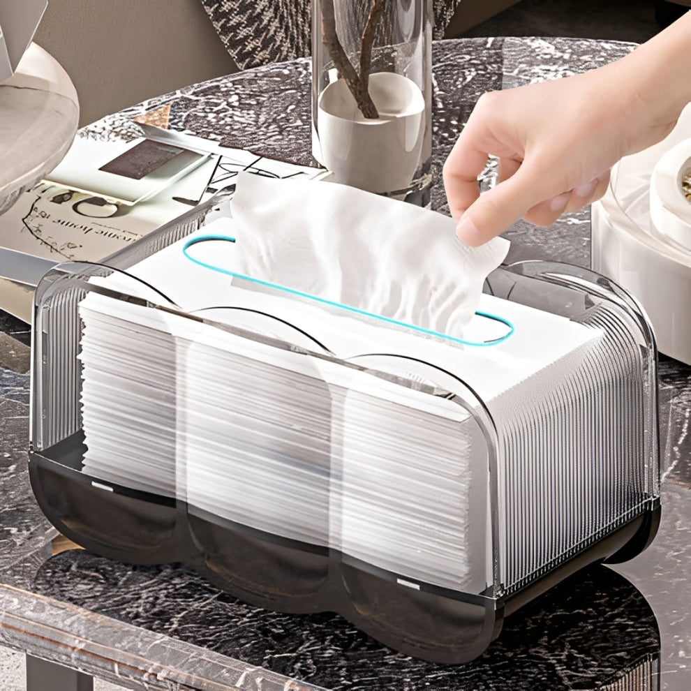 A person takes a tissue from a transparent tissue box on a marble table with their hand.