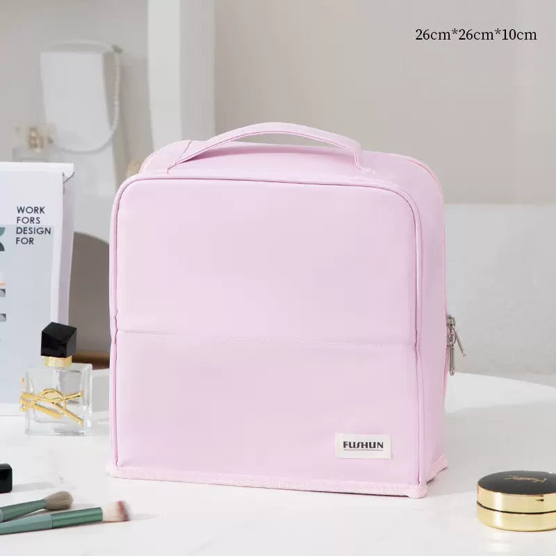 Travel Makeup Bag Cosmetic Organizer Case with a top handle and zipper closure, displayed on a white table with beauty items around it. The bag has a small white label reading 'FURUN'.