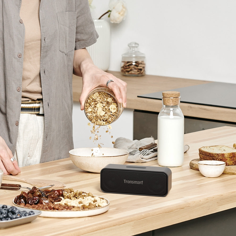A Women is Playing Tronsmart T2 Mini 2023 Portable Wireless Bluetooth Speaker While Cooking.