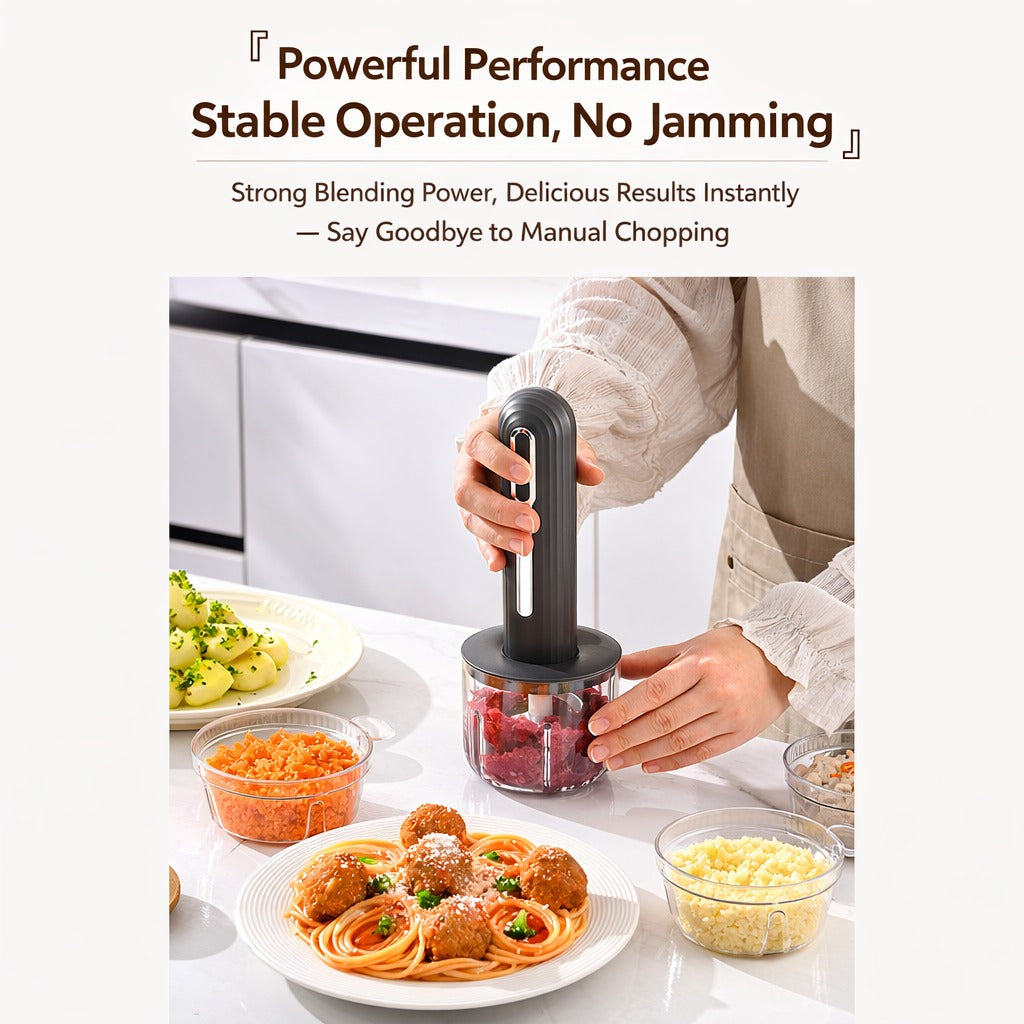 USB rechargeable food processor blender being used to chop meat in a clear container on a kitchen counter, surrounded by chopped vegetables, mashed potatoes, and a plate of spaghetti with meatballs.