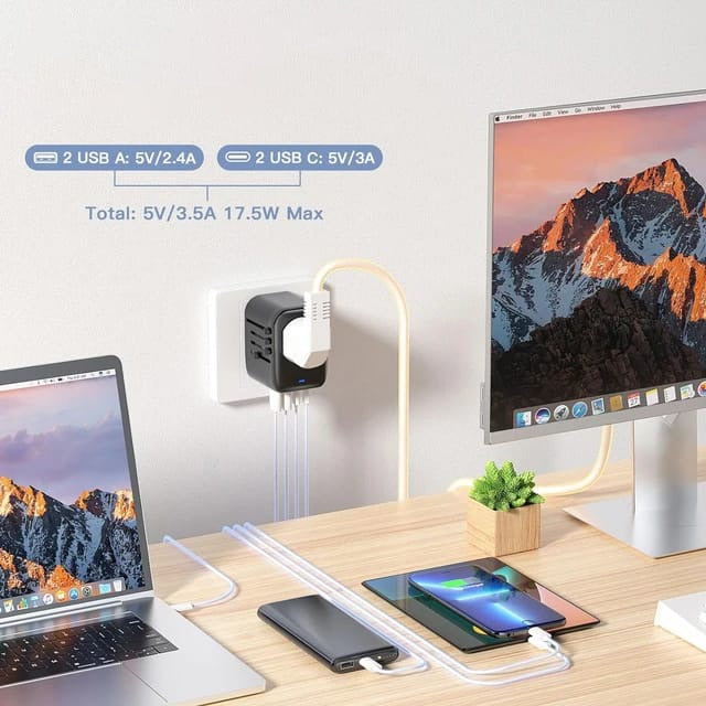 All-in-One Universal Travel Adapter with Multiple USB Ports placed on the table next to a mobile phone, laptop, and tablet, all of which are plugged into it