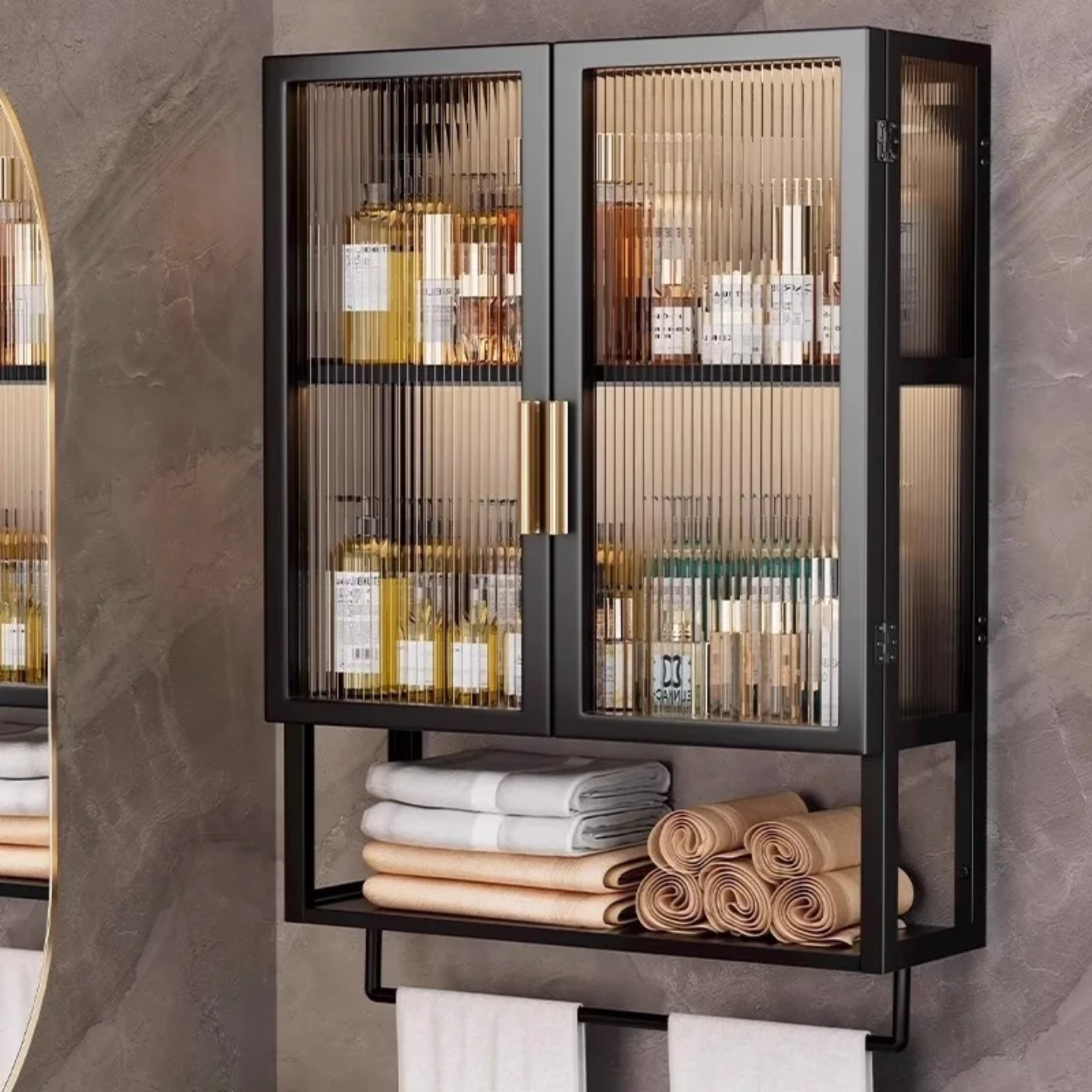 Wall-mounted storage organizer with ribbed glass doors, displaying neatly arranged bottles and cosmetics, and an open lower shelf holding folded towels.