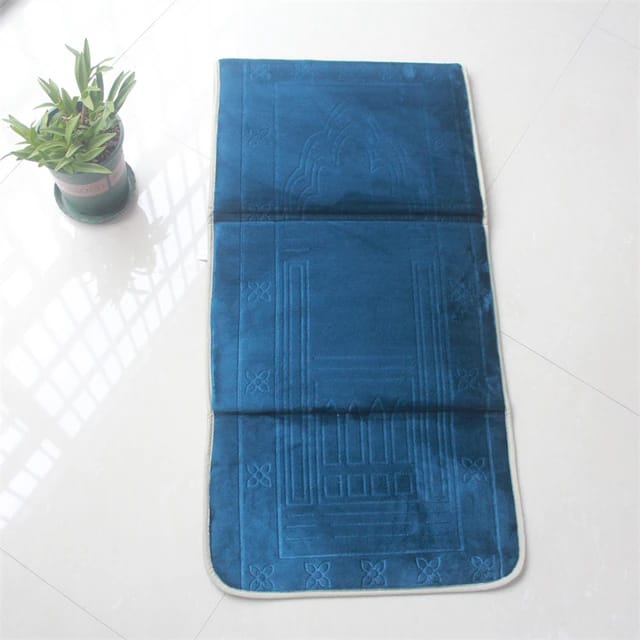 Fully opened Blue color Islamic Foldable Prayer Mat kept on a white surface next to a plant