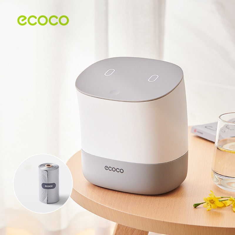 Showcasing Grey color Mini Desktop Waste Bin placed next to a glass cup on a table
