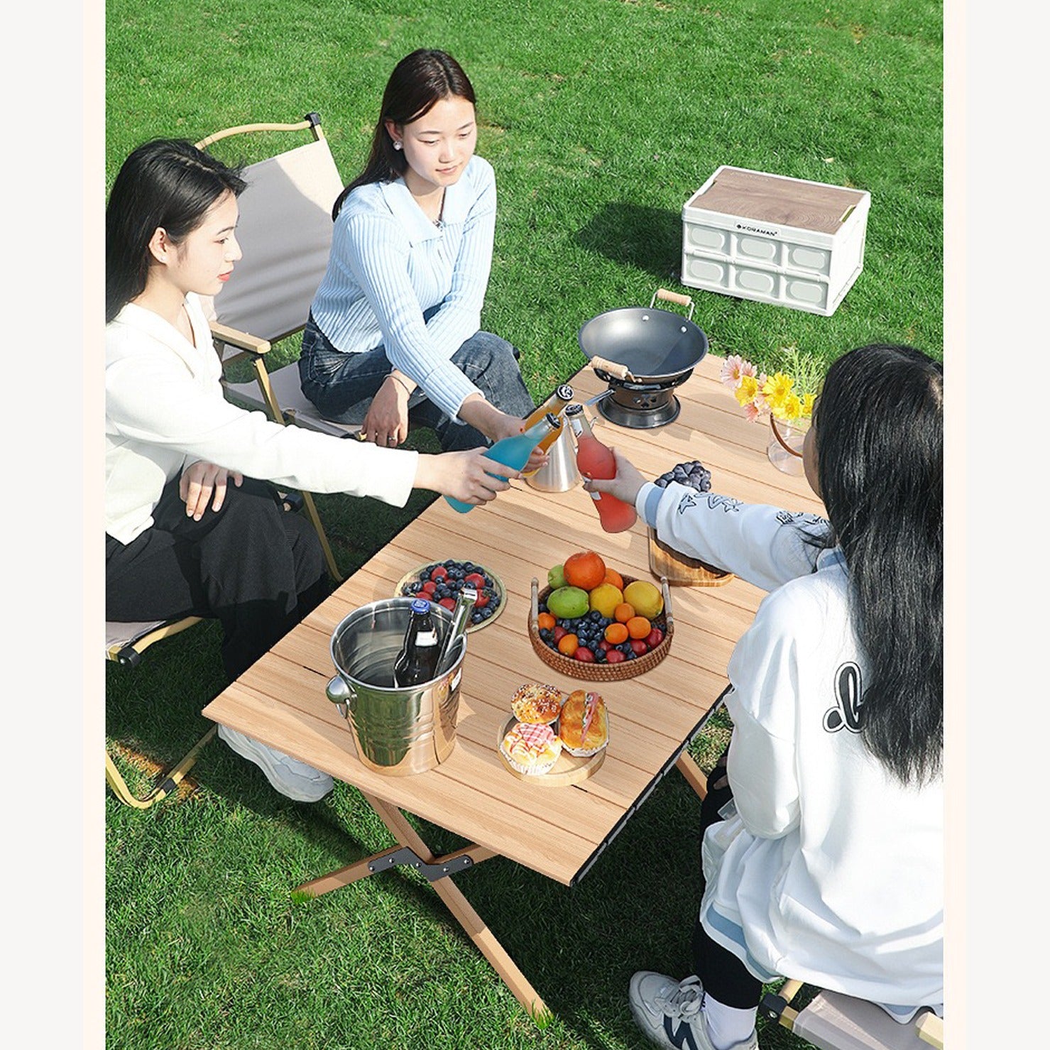 Outdoor Portable Camping Table with fruits,snacks and drinks placed on top of it being used by three ladies in a picnic at a park