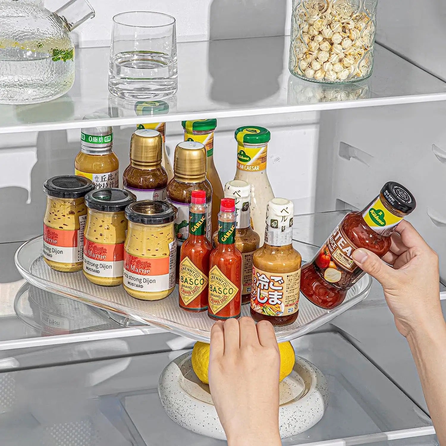 A person storing sauces in a 360° Rotating Fridge Tray and keeping it inside a fridge