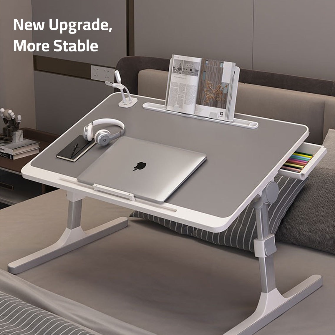 Laptop, headset, and book neatly arranged on the Adjustable Bed Laptop Table – a Foldable Lifting Desk for a versatile and comfortable workspace