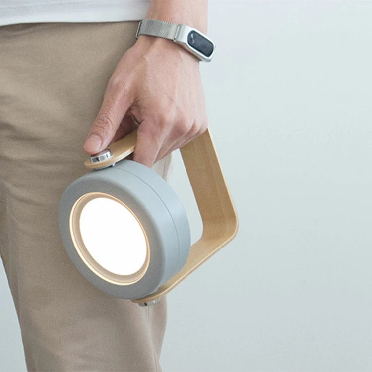 A man holding the Retractable Table Lamp with USB Rechargeable featuring a wooden handle