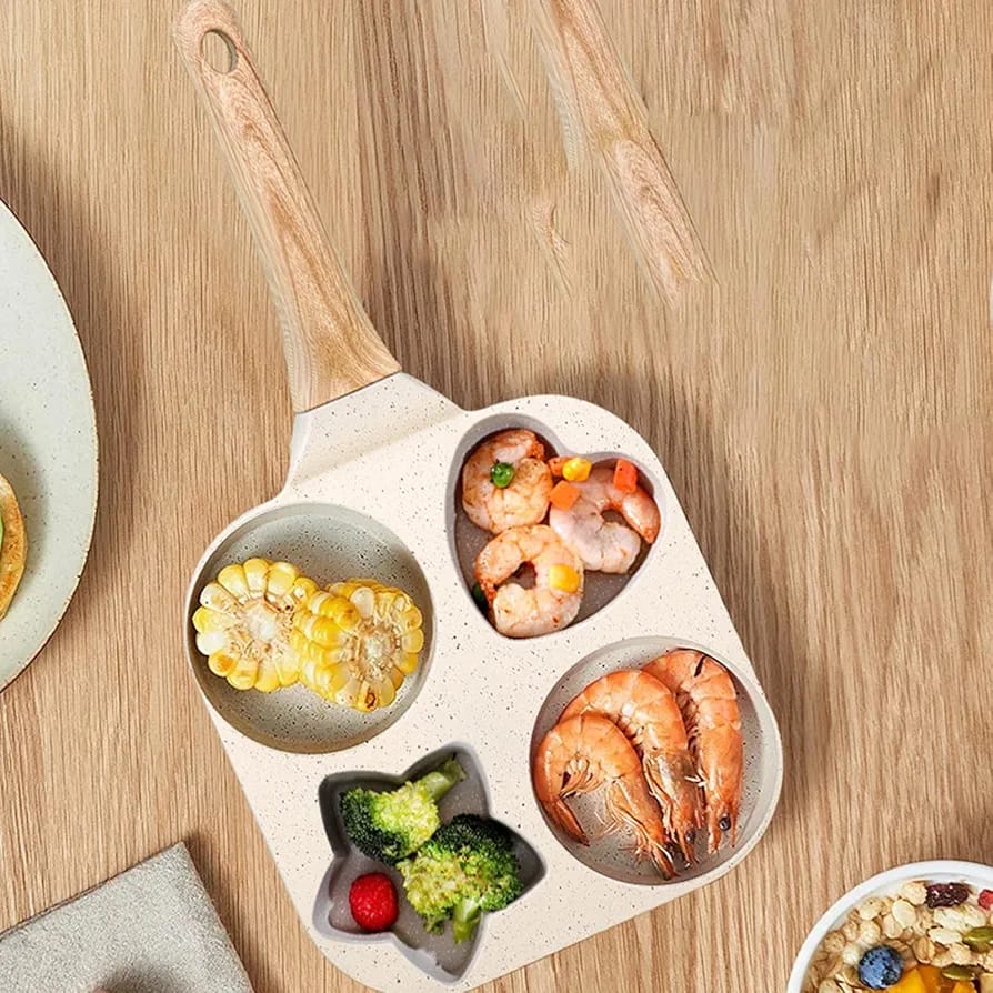 4 compartment pan with wooden handle, containing shrimp, corn, broccoli, and vegetables, placed on a wooden table.