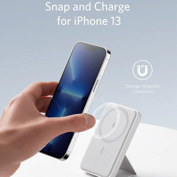 Someone is holding a phone while charging it with a 5000 mAh wireless portable charger