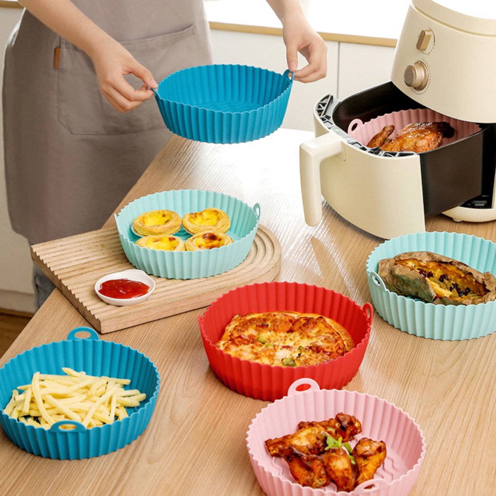 A woman carefully adds food to a non-stick baking pot in an air fryer basket in the kitchen