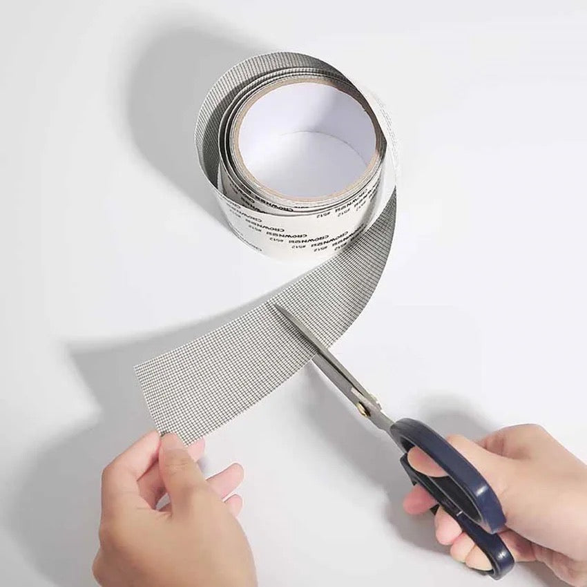 a scissors cutting a Self-adhesive Net Door Holes Repair Mesh Tape