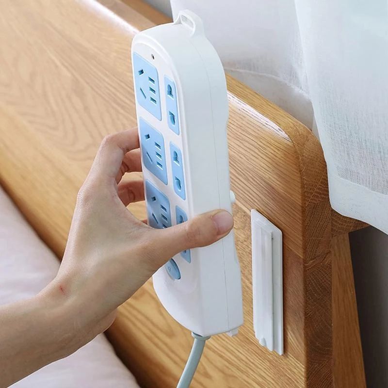 A hand trying to hang socket on Wall Mount Punch Free Socket Holder